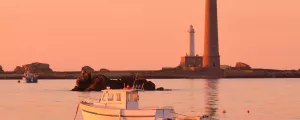 Bateaux amarrés devant le phare de l'Île Vierge au coucher de soleil
