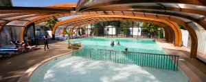 Piscine couverte avec des vacanciers nageant dans l'eau chauffée du camping La Marina à Messanges dans les Landes