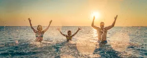 Famille jouant dans l'océan à éclabousser le photographe au coucher de soleil