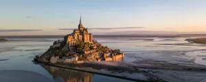 Mont Saint Michel à marée basse dabs les lumières dorées du lever de soleil