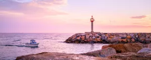 Saint Cyprien dans les Pyrénées Orientales, la rentée au port avec bateau au coucher du soleil dans cette ambiance rose de couleurs avec rochers et phare