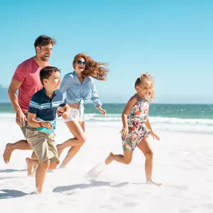 Famille courant sur le sable blanc au bord de la mer