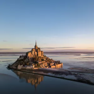 Mont Saint Michel à marée basse dabs les lumières dorées du lever de soleil