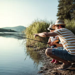 Père et enfant apprenant la pêche ensemble au bord d'un étang