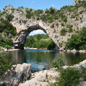 Pont en pierre au dessus d'une rivière et au milieu de la végétation en Auvergne