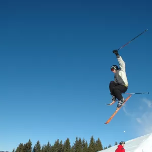 Skieur sautant au-dessus d'une piste de neige en montagne