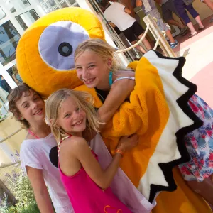 La mascotte Soly devant la Réception d'un camping avec des enfants