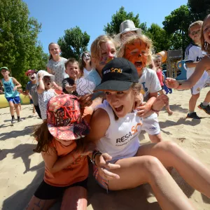 Animatrice entourée d'enfants dans un mini club de camping 4 étoiles