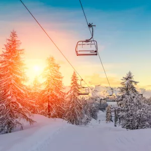 remontées mécaniques à la montagne, au-dessus de la neige et entre les sapins au lever de soleil