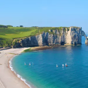 Falaises d'etretat avec des bateaux et des promeneurs pour profiter de ce lieu magnifique avec l'eau turquoise et les températures très agréables