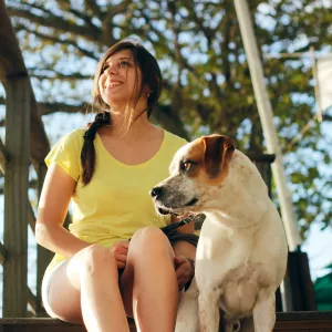 Chien heureux tenu en laisse par sa maîtresse dans un camping accueillant les animaux, illustrant l'atmosphère conviviale et détendue d'un séjour en pleine nature.