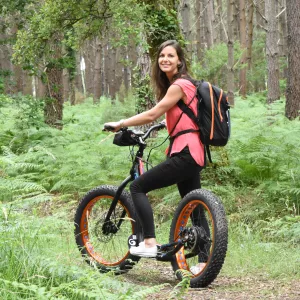book-activites-2025-v8-une femme-en-forêt-sur-son-velo-tout-terrain-entourée-de-fougères-souriante-agréable-pour-illustrer-activités-nature-aventure